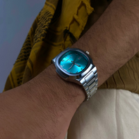 Model wearing a Casablancan Al-Majaz heritage Arabic numerals turquoise dial 43mm Watch with a yellow scarf in the background