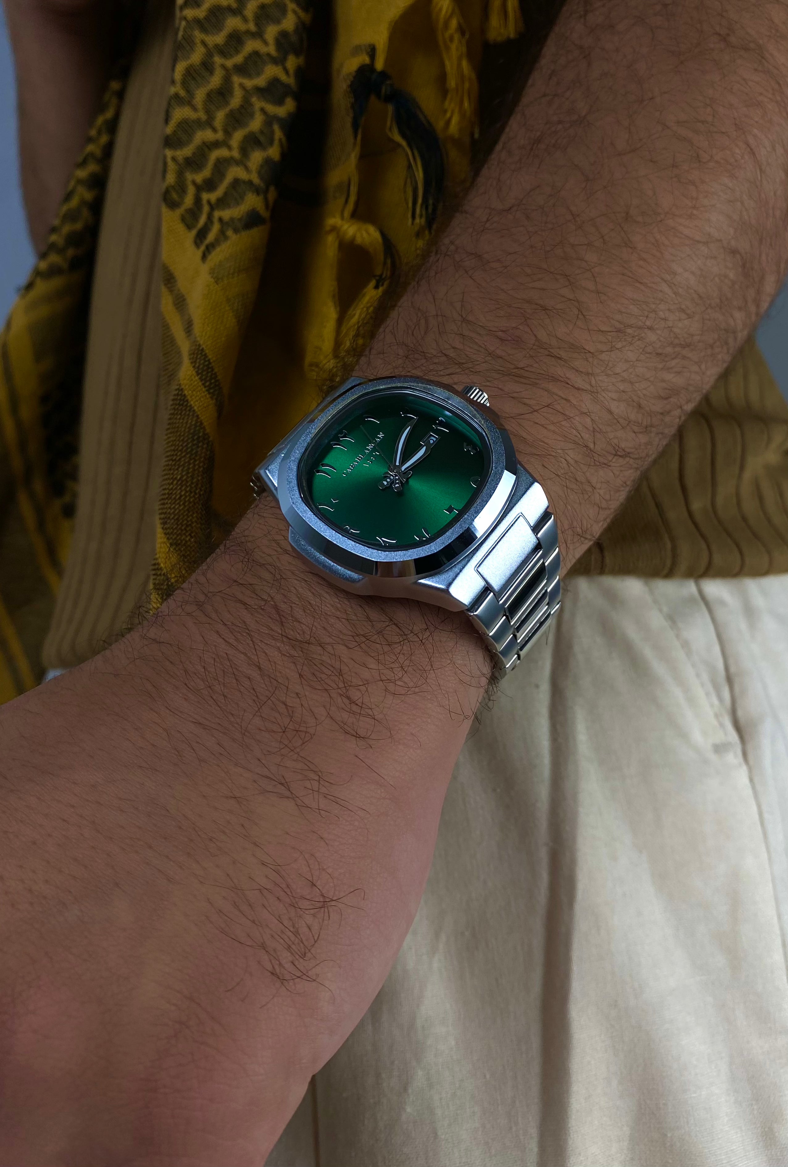 Close-up of a Casablancan Al-Riyadh Heritage Arabic numeral green dial 43mm Watch, against a blurred background.
