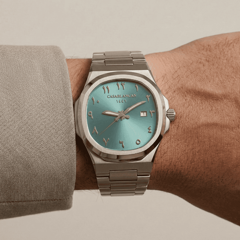 Casablancan Arabic dial watch watch with turquoise dial on a wrist against a neutral background